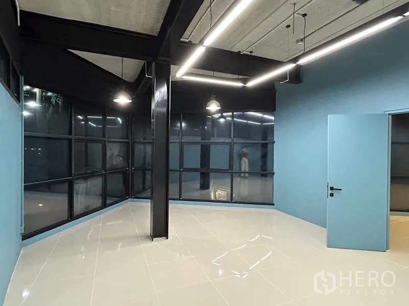 办公空间 出租在Chatuchak, Bangkok - 工业风转角办公室，环景玻璃、外露梁柱与时尚吊灯，铺设亮面瓷砖。