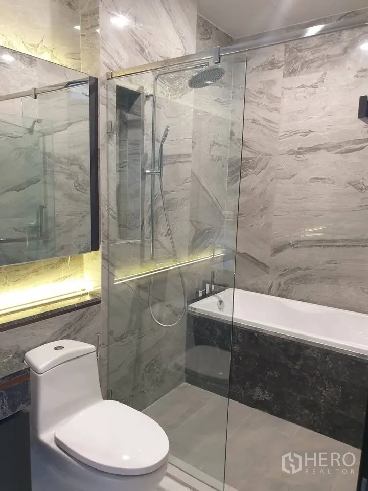 Condominium for rent in Watthana, Bangkok - Marble bathroom with glass-enclosed rain shower, bathtub, and modern toilet.