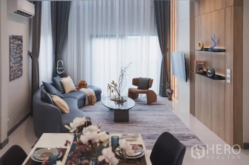 Detached House for rent in Bang Phli, Samut Prakan - Bright living and dining space with sofa, accent chair and built-in TV wall.
