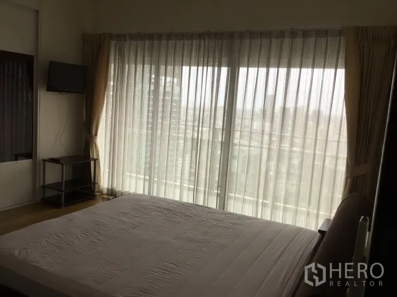 คอนโด ให้เช่าในWatthana, Bangkok - ห้องนอนมีผ้าม่านโปร่งปิดประตูกระจกบานเลื่อน และทีวีติดผนัง