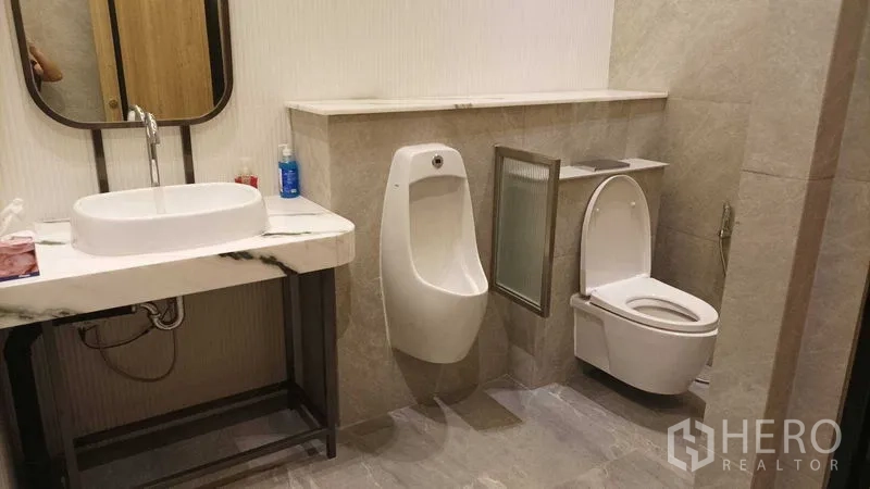 零售空间 出租 - 卫生间设大理石洗手台、小便斗与坐便器，灰色瓷砖铺设。