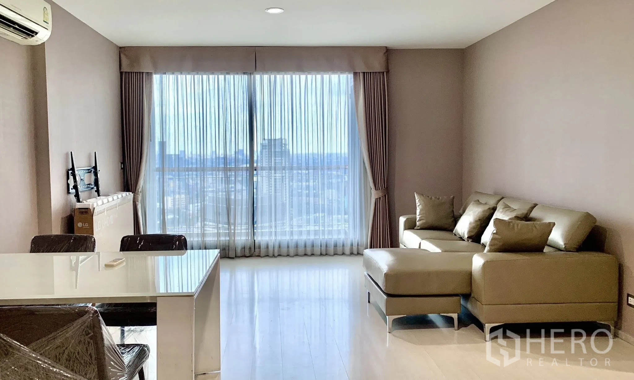 Condominium for rent in Khlong Toei, Bangkok - Open-plan living and dining area with large glazed doors, dining table, and city view.
