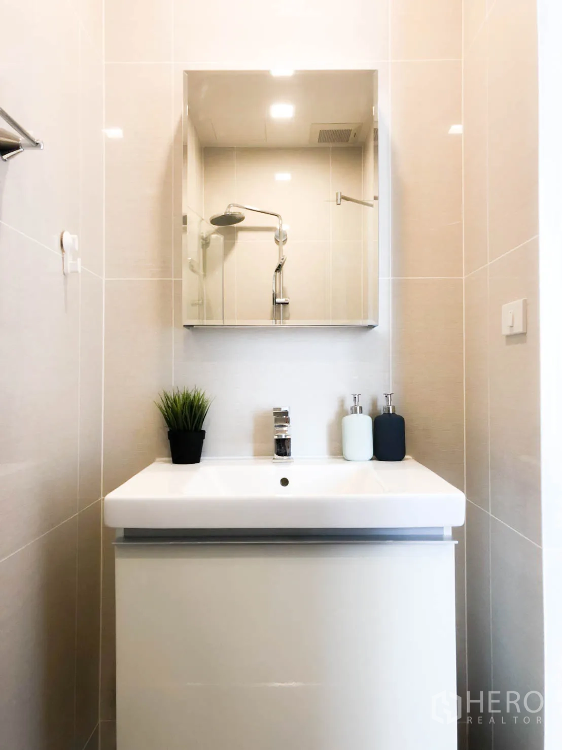Condominium for rent in Khlong Toei, Bangkok - Minimal vanity with mirror cabinet and sink in a tiled modern bathroom.