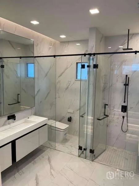 Detached House for rent in Bueng Kum, Bangkok - Luxurious bathroom with white marble tiles, glass-enclosed shower and matte black fixtures.