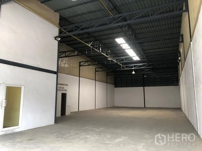 Warehouse for rent in Pak Kret, Nonthaburi - Open warehouse bay with high ceiling, skylights, and smooth concrete flooring.