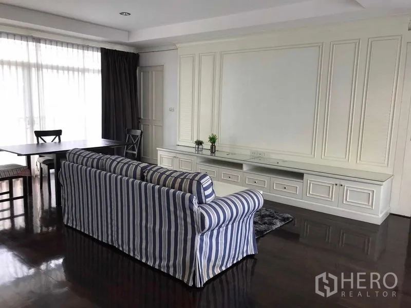 บ้าน ขายในWang Thonglang, Bangkok - ห้องนั่งเล่นพร้อมโซฟาลายทาง โต๊ะกินข้าว และผนังบิลท์อิน