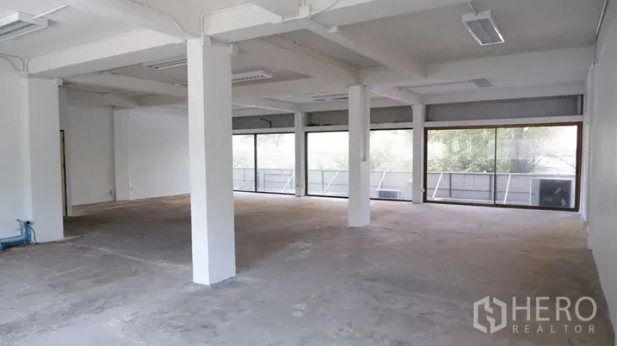 办公空间 出租在Watthana, Bangkok - 开放式办公楼层，多个立柱、顶灯与玻璃立面。