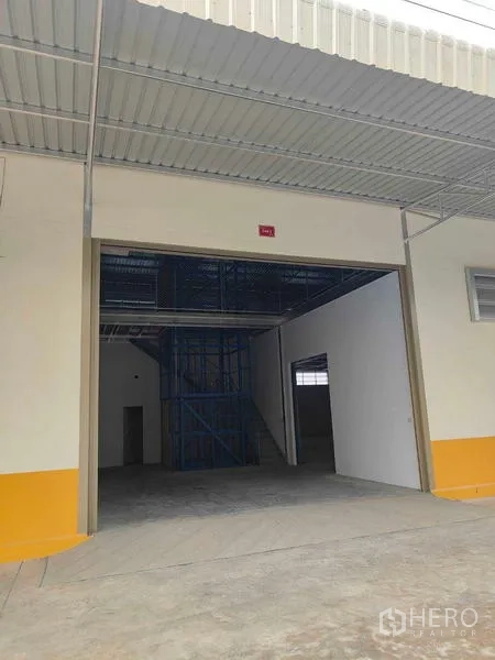 Warehouse for rent in Krathum Baen, Samut Sakhon - Open loading bay revealing high clearance and mezzanine racking structure inside.