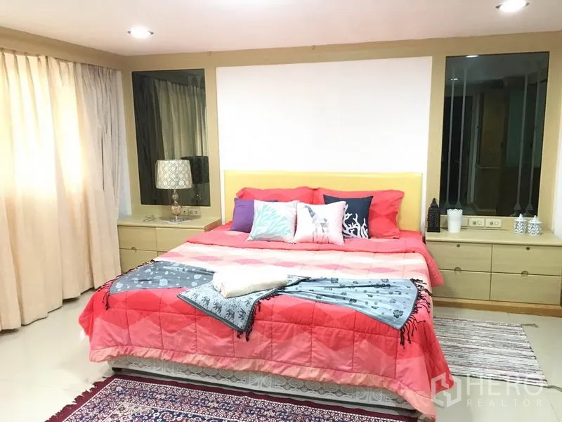 Townhouse for rent in Khlong Toei, Bangkok - Spacious master bedroom with king bed, red duvet, side tables, large windows and rugs.