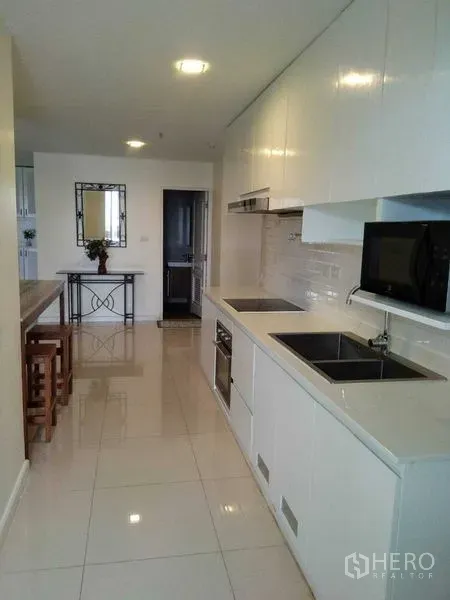 公寓 出租在Khlong Toei, Bangkok - 明亮的走廊式厨房，白色橱柜，嵌入式灶台、水槽和微波炉