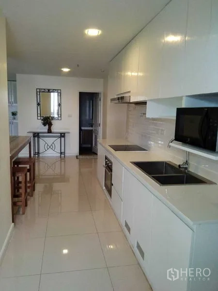 公寓 出租在Khlong Toei, Bangkok - 明亮的走廊式厨房，白色橱柜，嵌入式灶台、水槽和微波炉