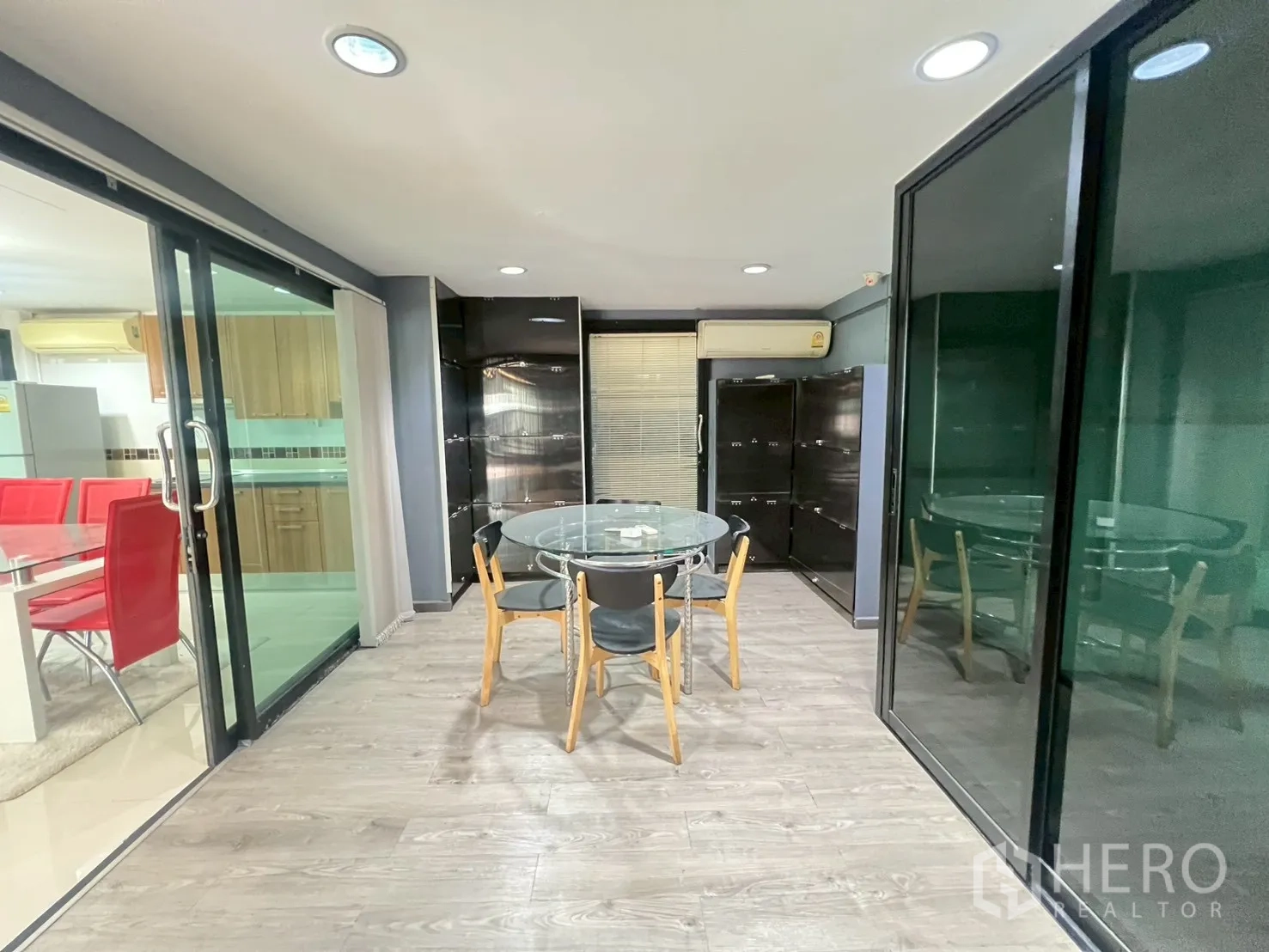Detached House for rent or sale in Wang Thonglang, Bangkok - Glass‑enclosed room with round table, built‑in cabinets and laminate floor.