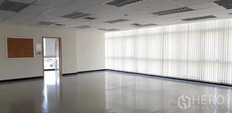 办公空间 出租在Khlong Toei, Bangkok - 采光明亮的角落工位，落地窗配百叶，光洁地面。