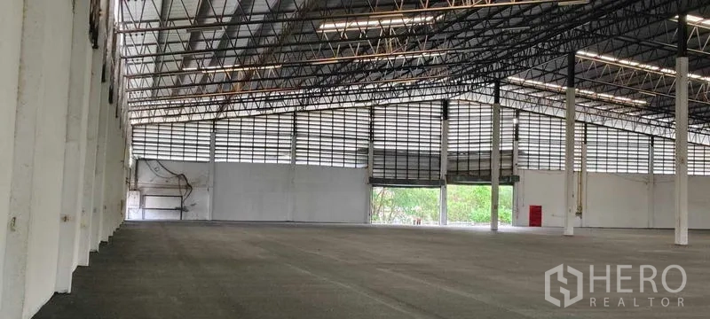 Warehouse for rent in Bang Pakong, Chachoengsao - Interior view showing steel trusses, skylights, white columns and forklift-ready flooring.