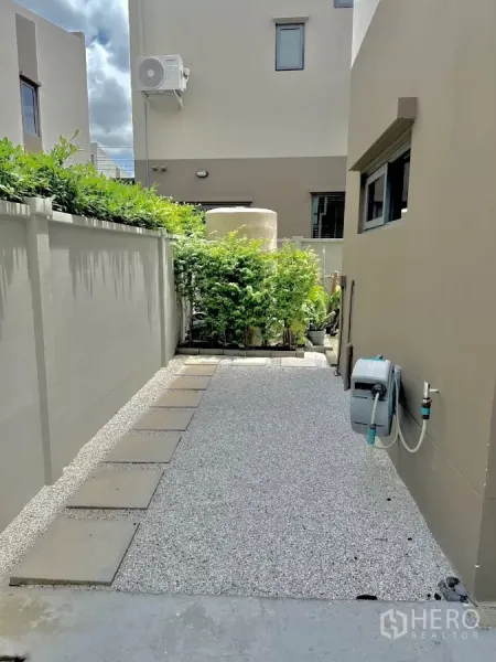บ้าน ให้เช่าหรือขายในPrawet, Bangkok - ทางเดินข้างบ้านโรยกรวด แผ่นทางเท้า และจุดต่อสายยาง ขนาบกำแพงสูง