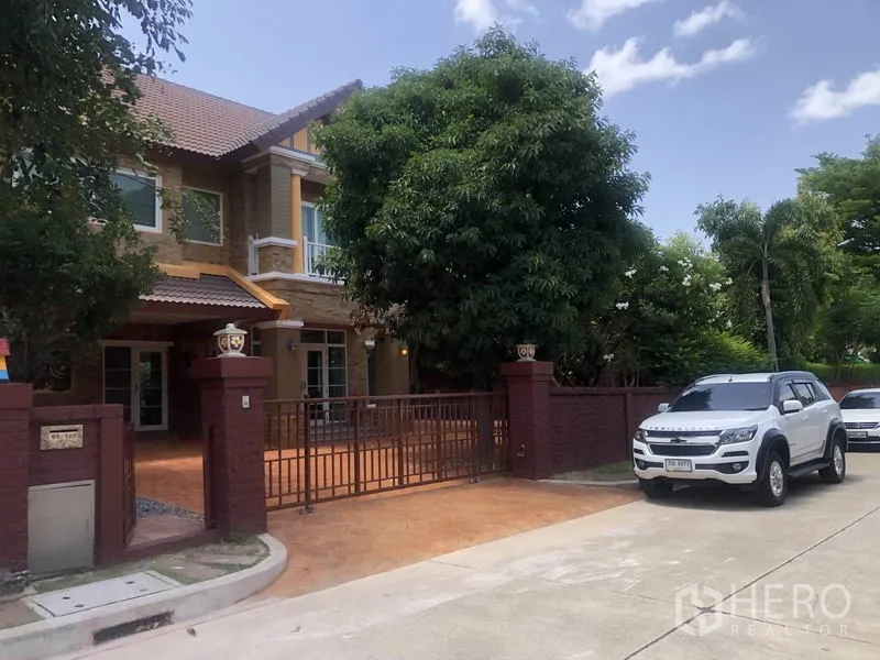 独立式住宅 出租或出售在Pak Kret, Nonthaburi - 安静社区道路前的庭院围栏与车道入口