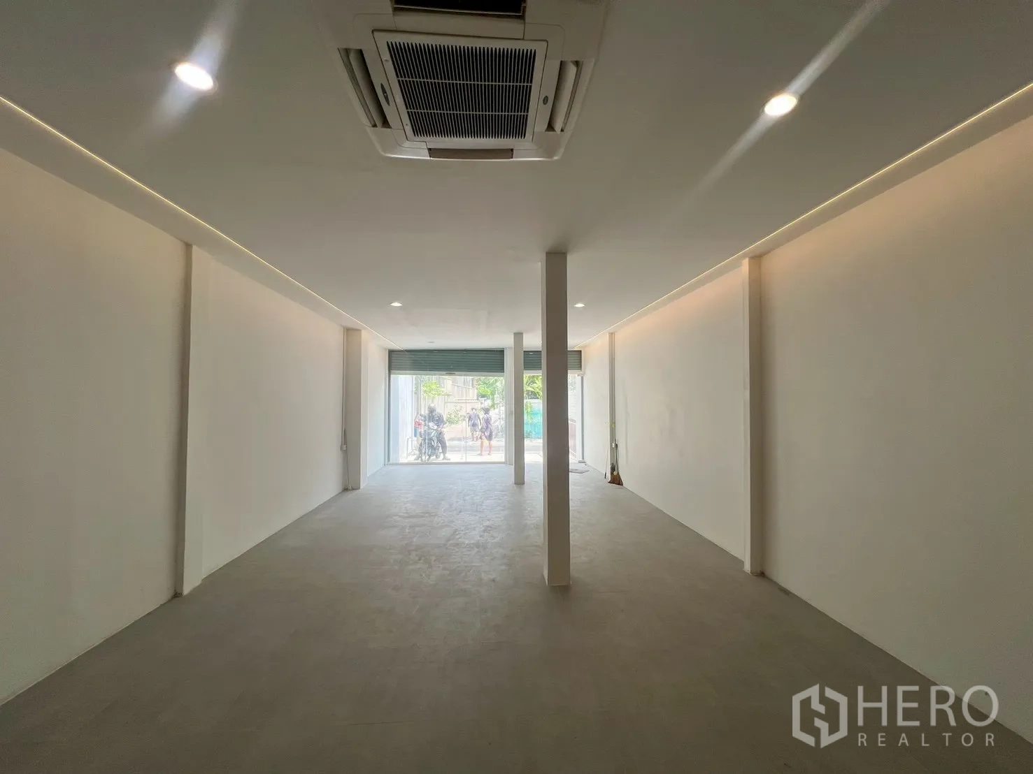 Home Office for rent in Watthana, Bangkok - Ground-floor open-plan space with recessed lighting and ceiling cassette air conditioner facing a glass storefront.