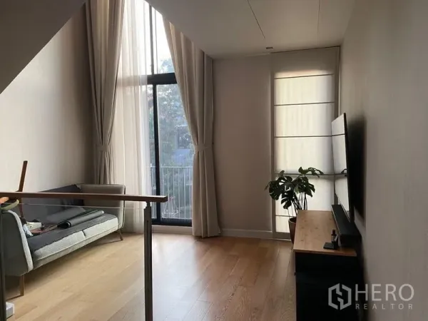 联排别墅 出售在Lat Phrao, Bangkok - 挑高客厅，阳台门、电视背景墙与浅色木地板。