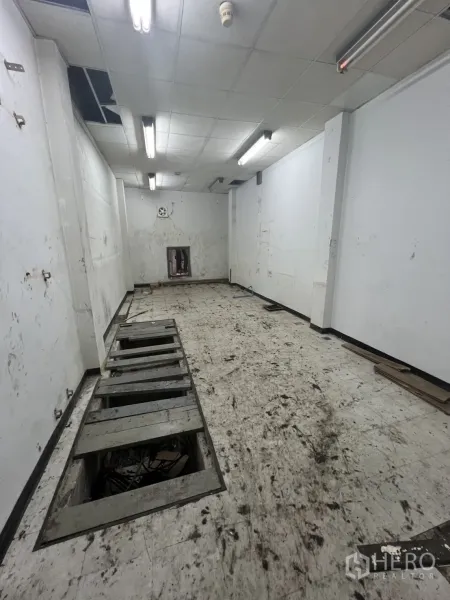 零售空间 出租在Watthana, Bangkok - 空置店铺内部，狭长开放式空间，日光灯与地面电缆槽。