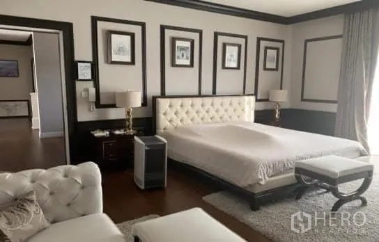 Detached House for sale in Bang Phli, Samut Prakan - Spacious master bedroom featuring a tufted headboard, decorative wall panels, and a cozy seating area.