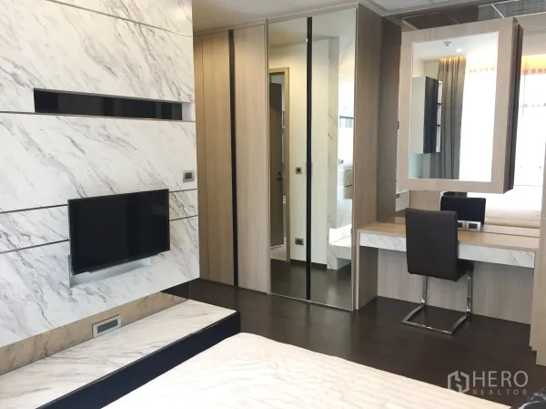 คอนโด ให้เช่าในWatthana, Bangkok - ห้องนอนตกแต่งผนังลายหินอ่อน ทีวีติดผนัง ตู้เสื้อผ้าบานกระจก และโต๊ะเครื่องแป้ง