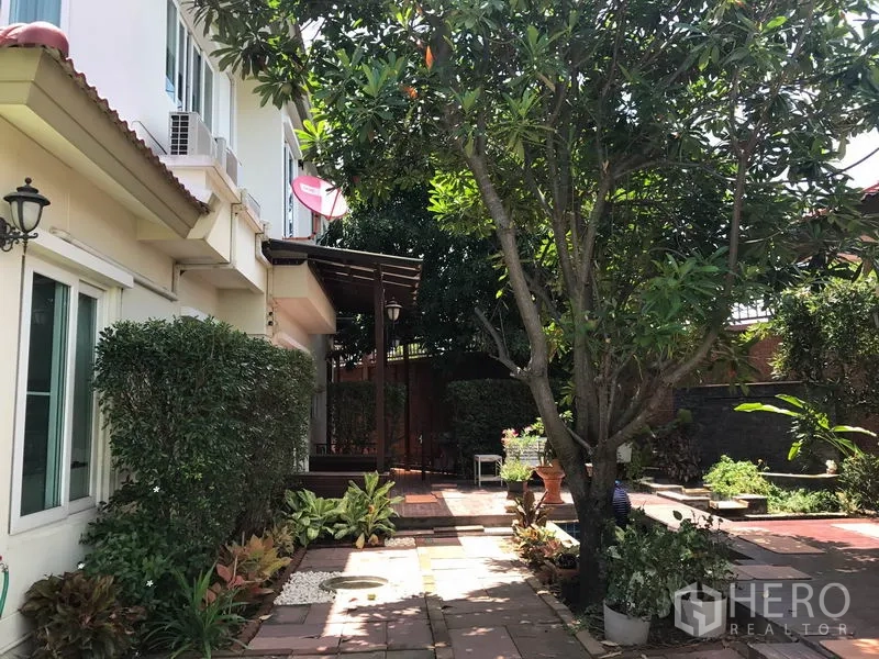 Detached House for sale in Pak Kret, Nonthaburi - Side patio with mature tree, canopy and tiled walkway beside the house.