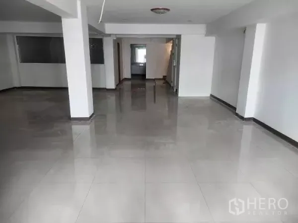 Shophouse for rent in Bang Rak, Bangkok - Spacious open interior with support columns and polished ceramic tiles.