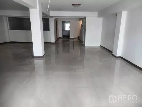 Shophouse for rent in Bang Rak, Bangkok - Spacious open interior with support columns and polished ceramic tiles.