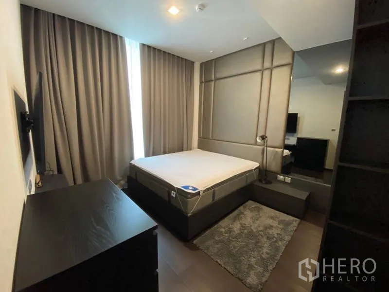 Condominium for rent in Watthana, Bangkok - Cozy bedroom featuring upholstered accent wall, queen bed base and dark wood flooring.