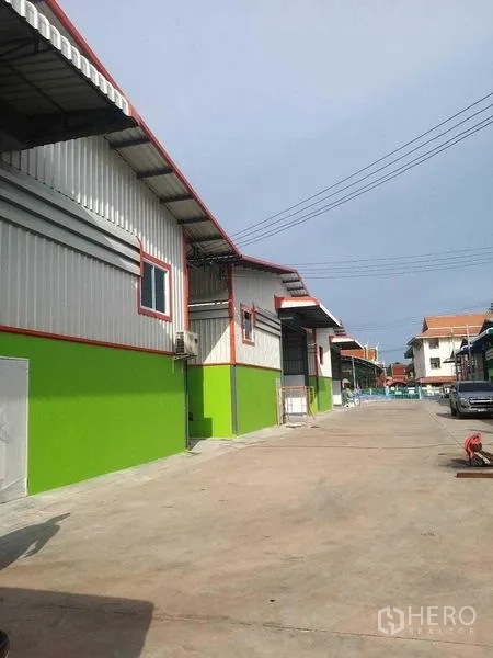 Warehouse for rent in Bang Khun Thian, Bangkok - Row of warehouses with a wide internal road for truck access in the compound.
