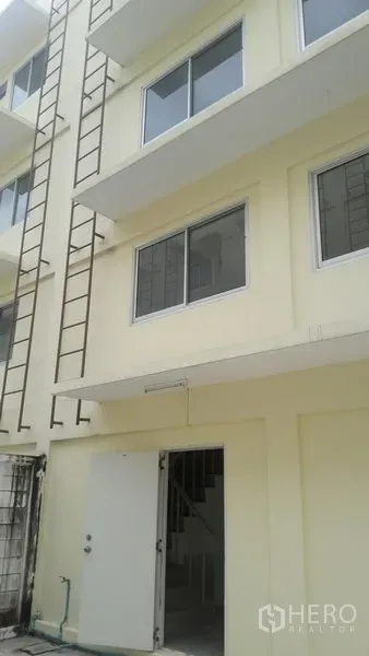 Office Space for sale in Khlong Luang, Pathum Thani - Rear exterior with cream facade, windows and vertical steel ladder access beside the service door.