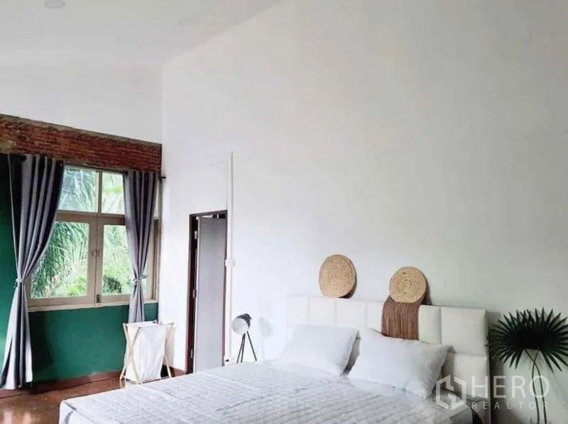 Detached House for rent in Pathum Wan, Bangkok - Airy bedroom view with white bed, curtains and exposed brick trim beneath the ceiling.
