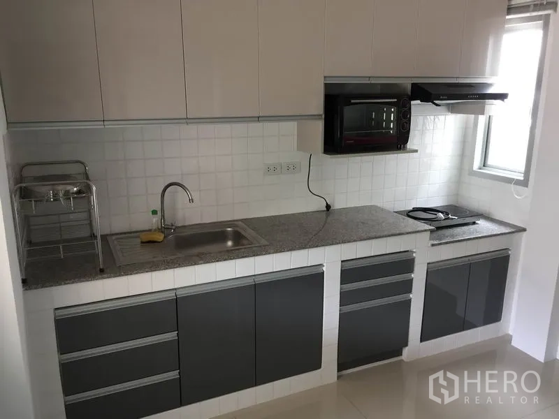 Detached House for rent or sale in Saphan Sung, Bangkok - Modern built-in kitchen with white tile backsplash, granite countertop, dark lower cabinets and window.