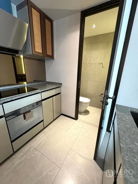 Condominium for rent in Watthana, Bangkok - Fitted kitchen with built-in appliances and access to a bathroom.