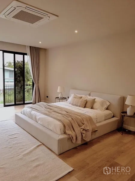บ้าน ให้เช่าในKhlong Toei, Bangkok - ห้องนอนหลัก เตียงคิงส์ โทนสีอบอุ่น พื้นไม้ และหน้าต่างเต็มบานติดระเบียง
