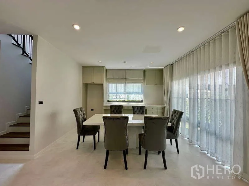 独立式住宅 出租在Bang Phli, Samut Prakan - 餐区配四把软包餐椅，临大窗与窗帘。