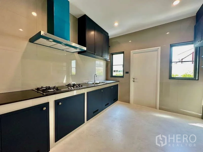 独立式住宅 出租在Bang Phli, Samut Prakan - 封闭式现代厨房，燃气灶、烟机与深蓝橱柜。