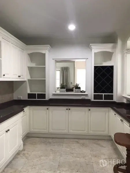 独立式住宅 出租在Phra Khanong, Bangkok - 明亮U形厨房，白色橱柜、深色台面，带开放搁架与酒格。