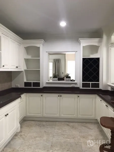 独立式住宅 出租在Phra Khanong, Bangkok - 明亮U形厨房，白色橱柜、深色台面，带开放搁架与酒格。