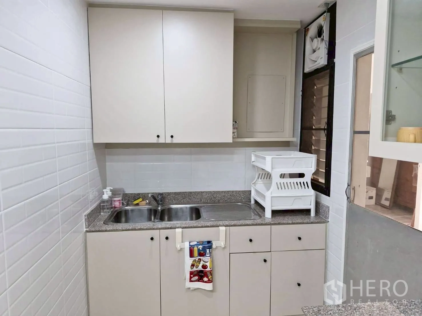 Condominium for rent in Khlong Toei, Bangkok - Compact kitchen corner with double stainless sink, beige cabinets and granite countertop.