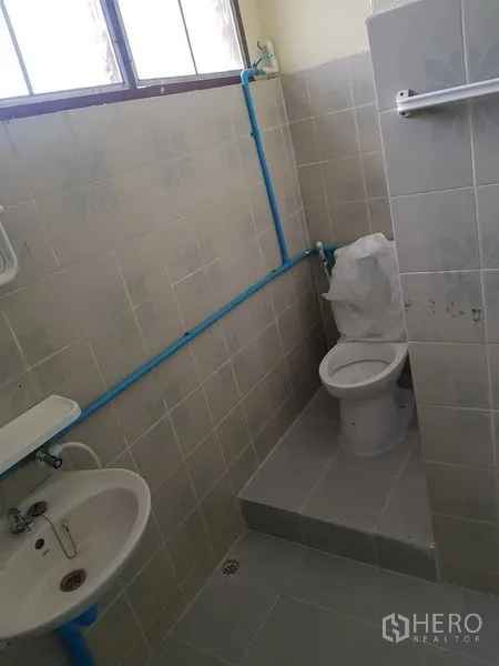 พื้นที่ขายปลีก ให้เช่าในKhlong Toei, Bangkok - ห้องน้ำกระเบื้องสีเบจ มีหน้าต่าง อ่างล้างมือ โถสุขภัณฑ์ และท่อประปาสีฟ้า