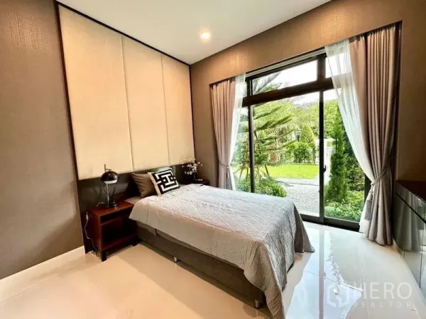 บ้าน ให้เช่าในLat Krabang, Bangkok - ห้องนอนชั้นล่าง วิวสวน หน้าต่างสูงจรดพื้น ผ้าม่านโทนอ่อน