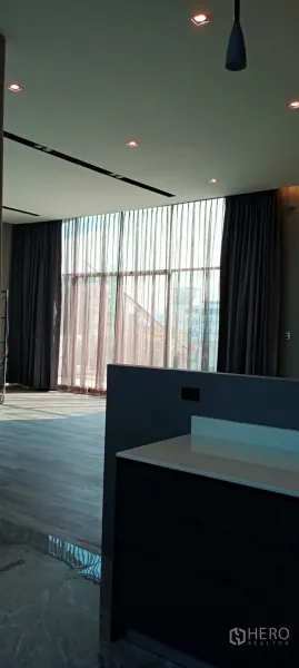 สำนักงาน ให้เช่า - มุมสำนักงานที่มีกระจกเต็มผนังพร้อมผ้าม่านกรองแสง ข้างเคาน์เตอร์แพนทรีสวยทันสมัย.