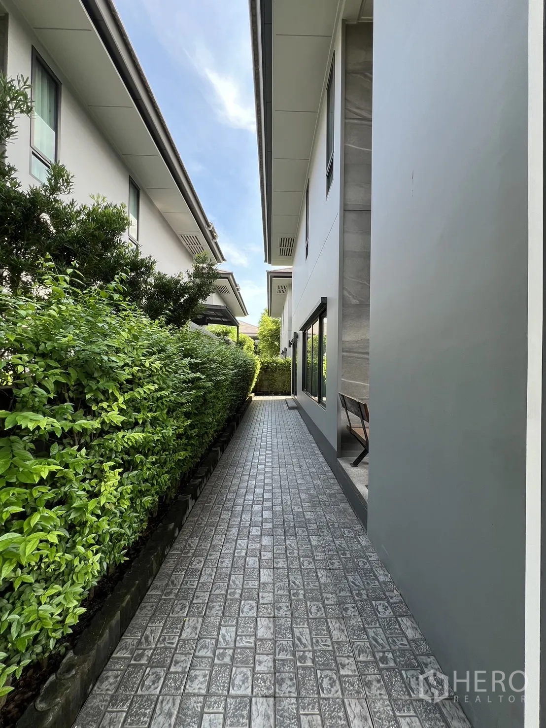 Detached House for rent or sale in Bang Kapi, Bangkok - Rear side walkway with AC units and tall hedges.