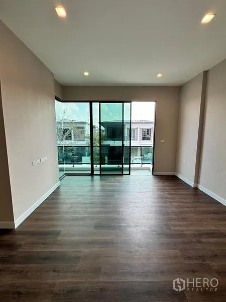 Detached House for rent or sale - Living area with sliding glass doors opening to a large balcony and wood floors.