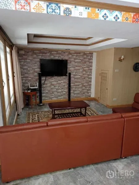 ทาวน์เฮาส์ ให้เช่าในKhlong Toei, Bangkok - ห้องนั่งเล่นพร้อมโซฟาหนัง ผนังอิฐตกแต่ง และฝ้าหลุมในทาวน์เฮาส์เอกมัย