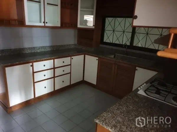 Condominium for rent in Watthana, Bangkok - Separate U-shaped kitchen with granite countertops, gas hob and white-and-wood cabinetry.