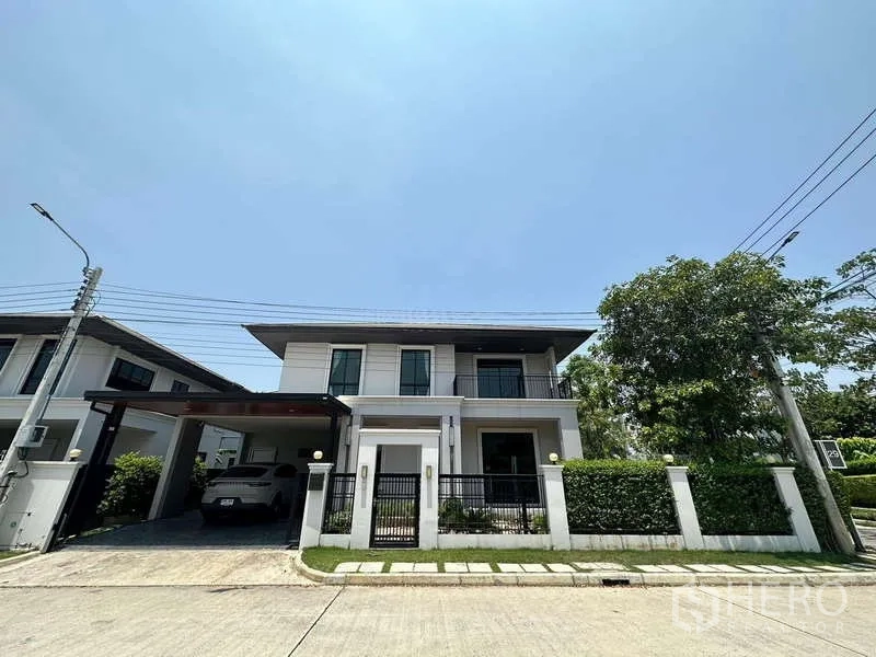 独立式住宅 出售在Prawet, Bangkok - 现代两层独栋别墅正面，带围栏大门、车棚与绿篱。