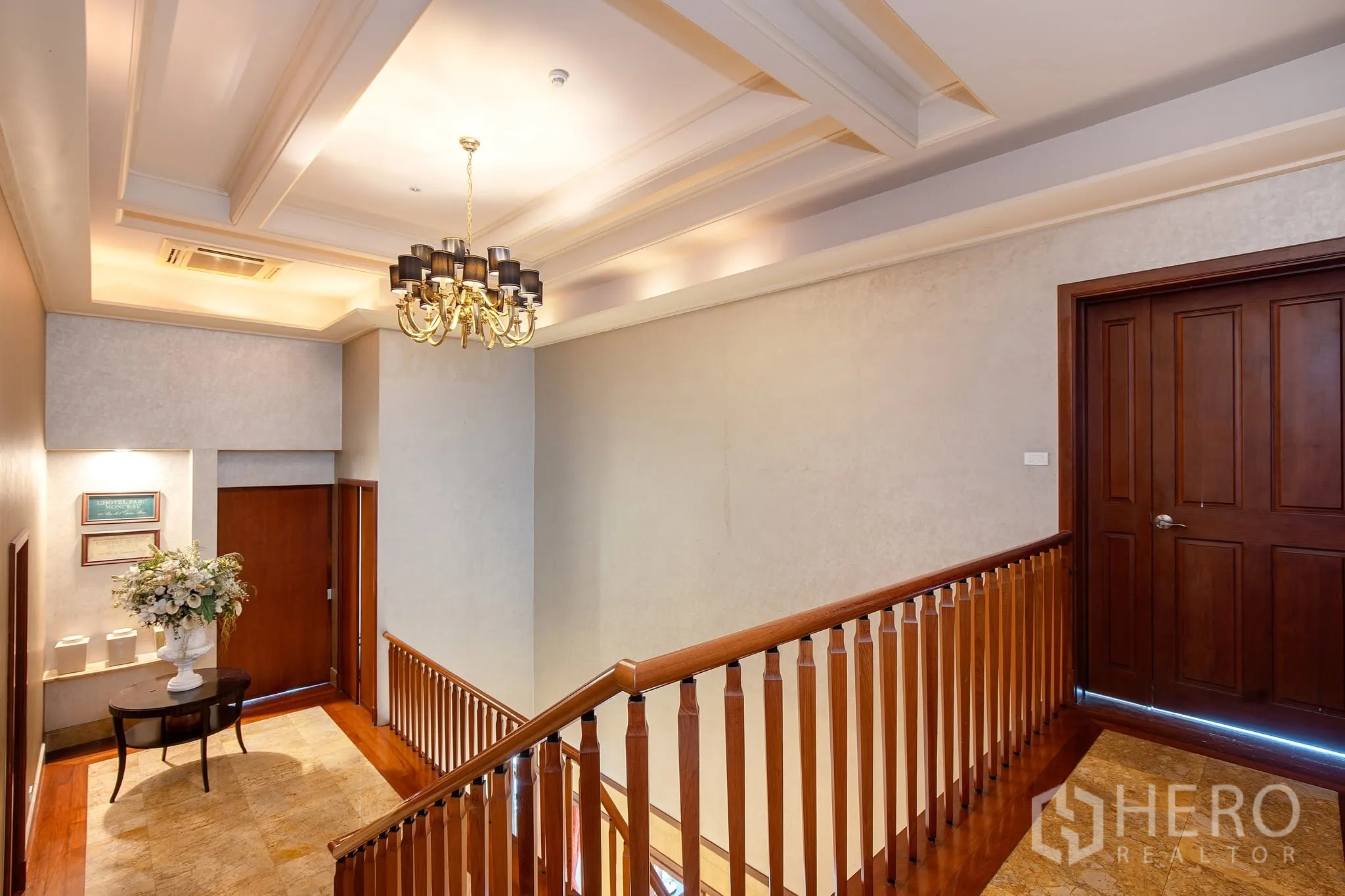 独栋房屋 for rent or sale in Watthana, Bangkok - 楼梯平台配木扶手、吊灯与大理石地面。