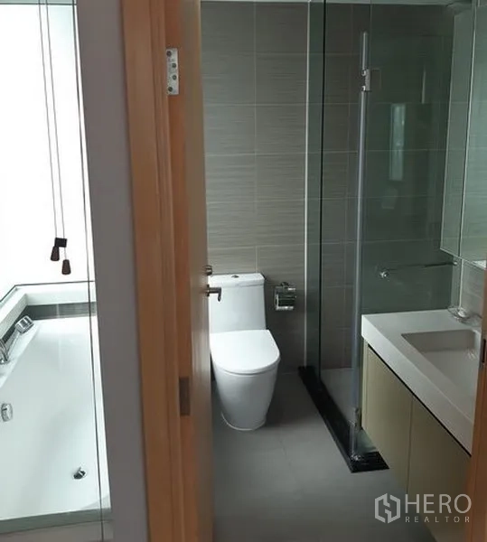Condominium for rent in Khlong Toei, Bangkok - Bathroom with separate glass shower, vanity and a soaking bathtub in an adjacent wet area.